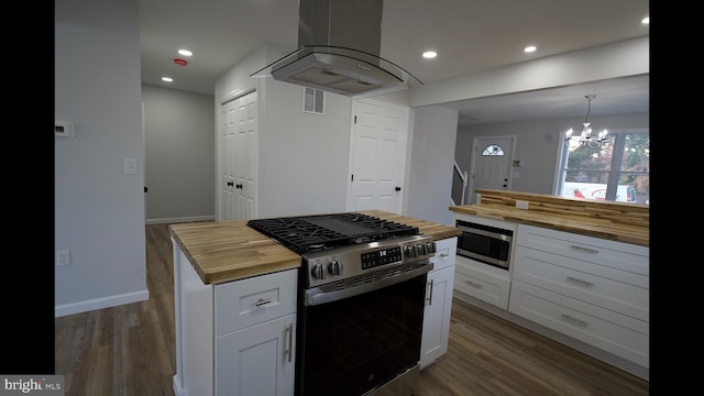 kitchen featuring butcher block counters, wood finished floors, appliances with stainless steel finishes, and island range hood