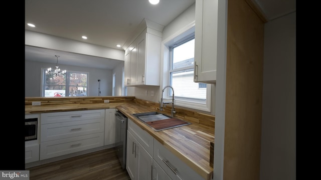 kitchen with stainless steel appliances, white cabinetry, a sink, and wood counters