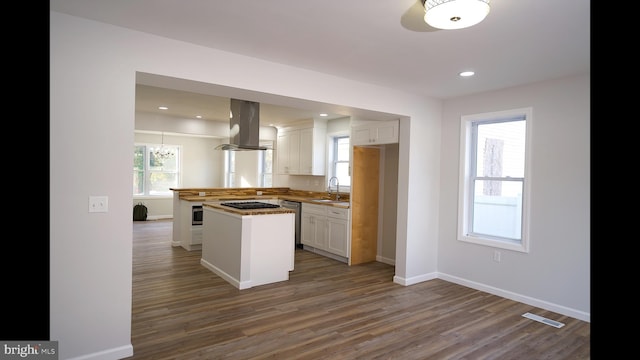 kitchen featuring visible vents, appliances with stainless steel finishes, white cabinetry, island range hood, and wood finished floors