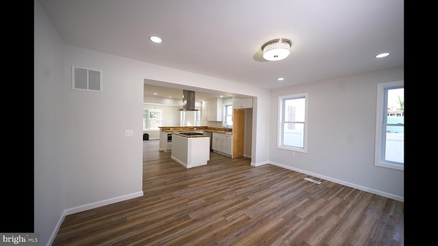 kitchen featuring island range hood, wood finished floors, a sink, visible vents, and open floor plan