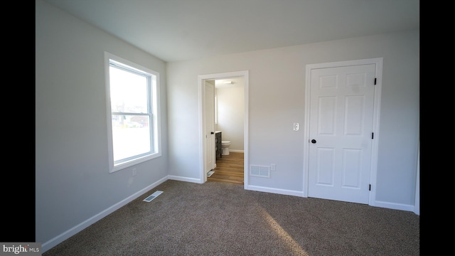 unfurnished bedroom featuring carpet floors, visible vents, connected bathroom, and baseboards