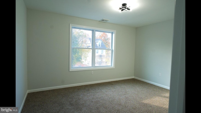 spare room featuring carpet flooring, visible vents, and baseboards