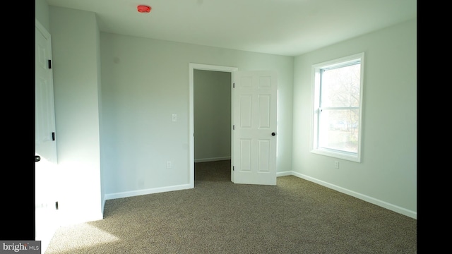 unfurnished bedroom featuring dark colored carpet and baseboards