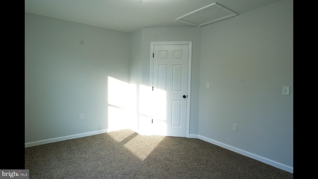 unfurnished room featuring attic access, baseboards, and carpet flooring