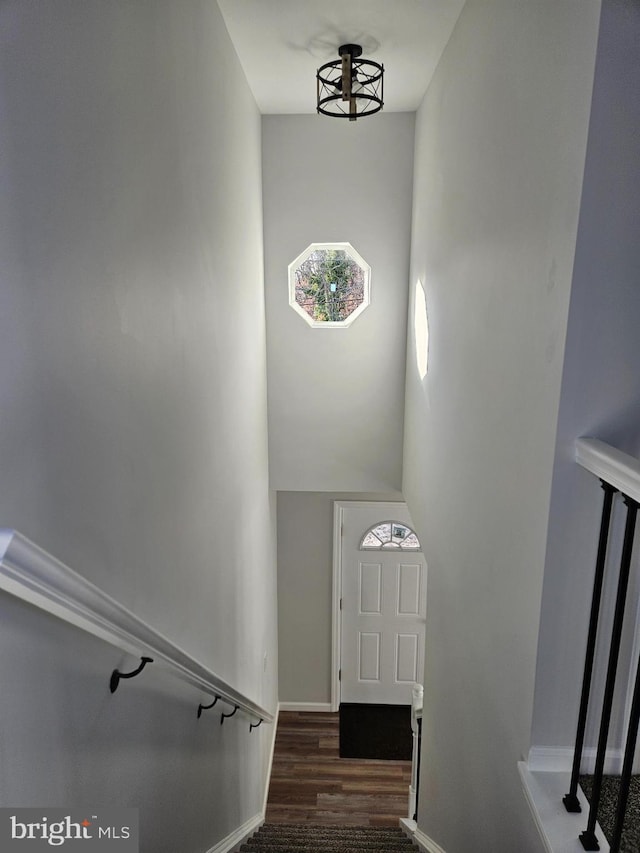 stairway with a towering ceiling, baseboards, and wood finished floors