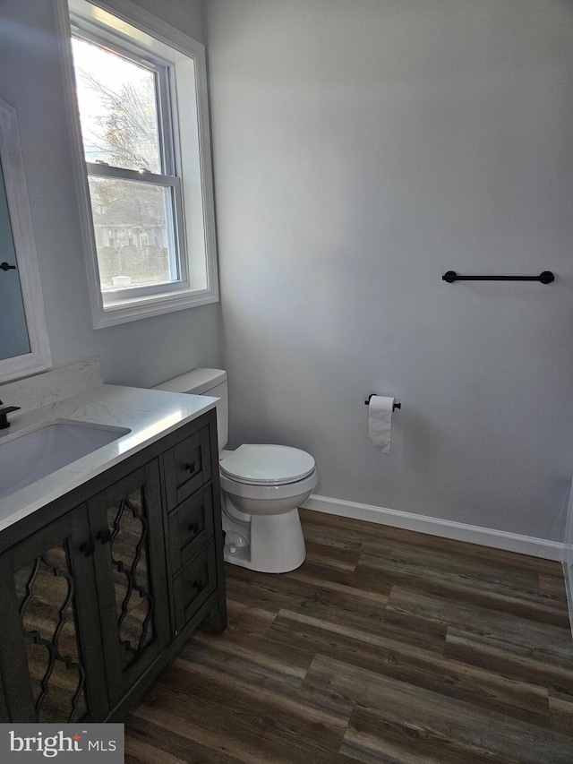 bathroom featuring baseboards, vanity, toilet, and wood finished floors