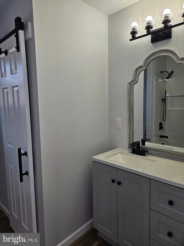 bathroom featuring wood finished floors, vanity, baseboards, and walk in shower