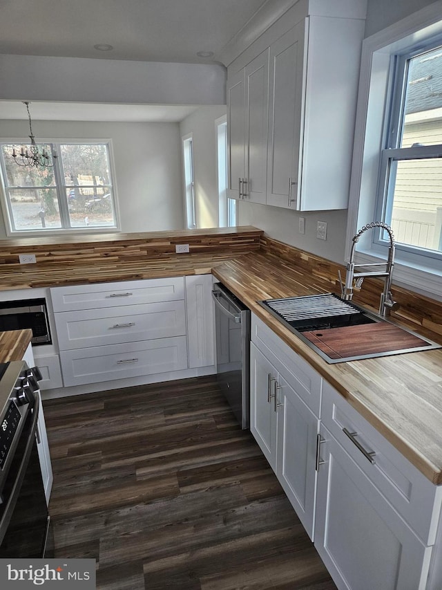 kitchen featuring butcher block counters, dark wood-style flooring, a sink, and appliances with stainless steel finishes