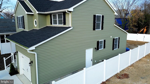 view of side of home featuring a shingled roof and a fenced backyard