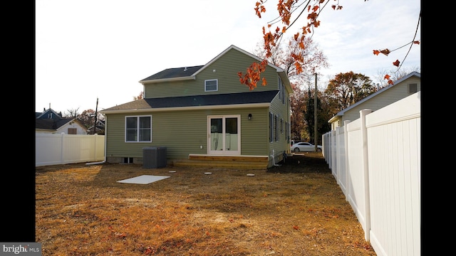 rear view of property featuring a lawn, fence, central AC, and french doors