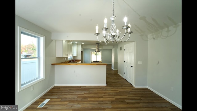 kitchen with a chandelier, a peninsula, dark wood-style flooring, visible vents, and white cabinets