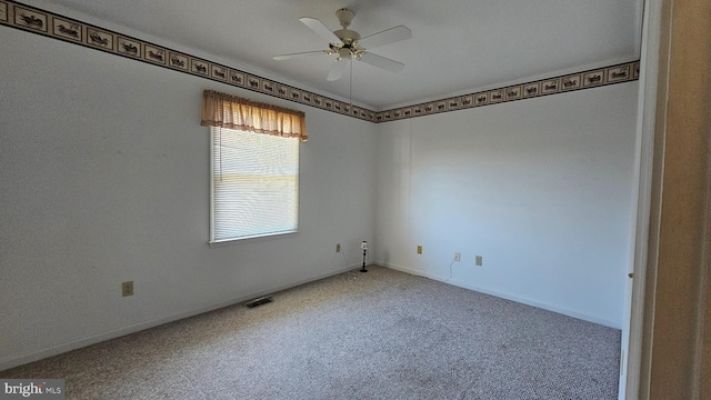 carpeted spare room featuring baseboards, visible vents, and a ceiling fan