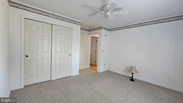 unfurnished bedroom with ceiling fan, baseboards, ornamental molding, a closet, and carpet