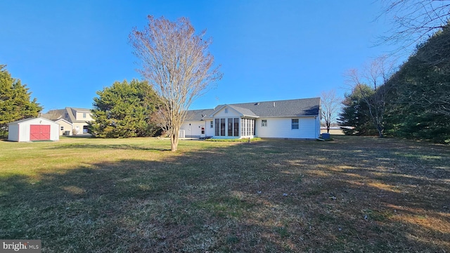 rear view of house featuring a sunroom, a shed, an outdoor structure, and a yard