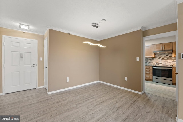 interior space featuring ornamental molding, light wood-type flooring, a textured ceiling, and baseboards