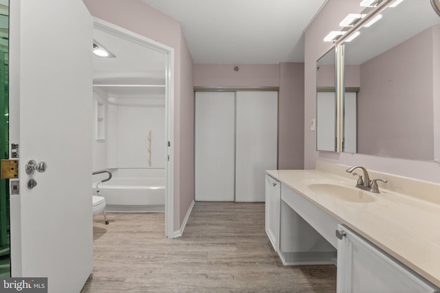 bathroom with toilet, tub / shower combination, wood finished floors, and vanity