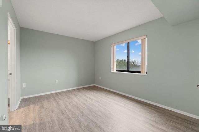 spare room with wood finished floors and baseboards