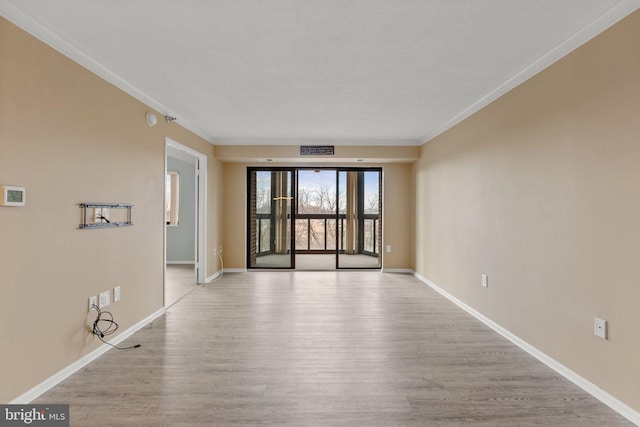 unfurnished room with visible vents, baseboards, wood finished floors, and ornamental molding