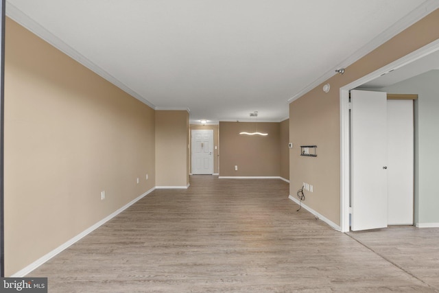 empty room featuring baseboards, ornamental molding, and light wood-style floors