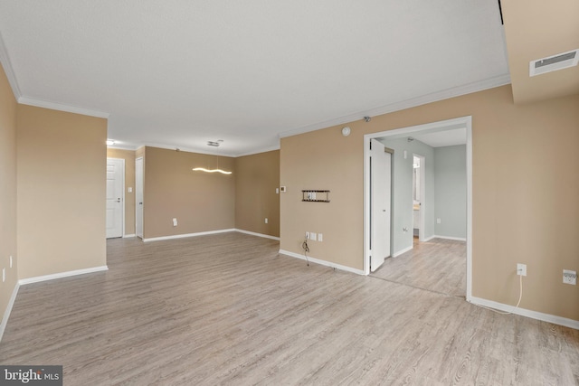 empty room featuring crown molding, light wood-style flooring, and baseboards