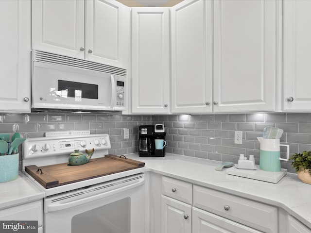 kitchen featuring white appliances, white cabinets, light countertops, and backsplash