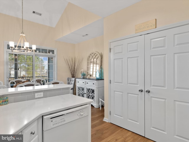 kitchen with light wood finished floors, visible vents, decorative light fixtures, vaulted ceiling, and white dishwasher