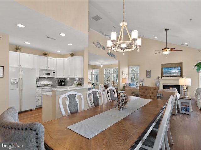 dining room with light wood-style flooring, recessed lighting, visible vents, and a lit fireplace