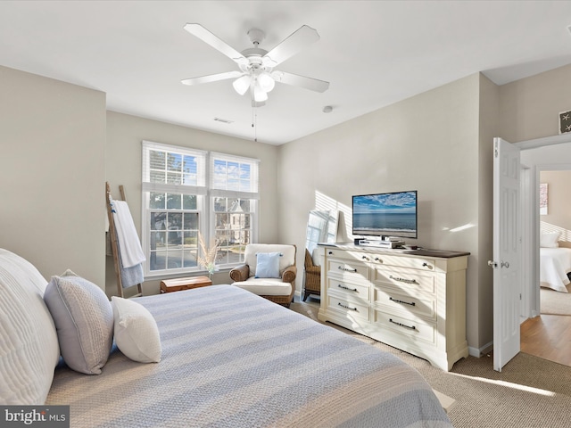 bedroom with visible vents, light colored carpet, baseboards, and a ceiling fan