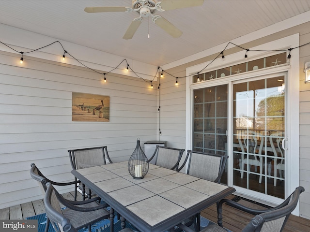 wooden terrace with outdoor dining area and ceiling fan