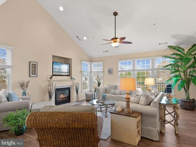 living area featuring a glass covered fireplace, wood finished floors, visible vents, and a wealth of natural light