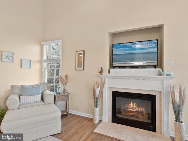 living area featuring wood finished floors, baseboards, and a tile fireplace