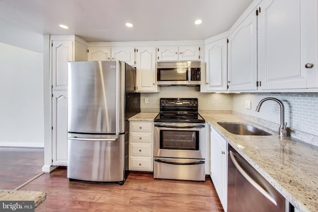 3101 New Mexico Ave NW Unit 847, Washington, DC 20016 - kitchen with wood finished floors, light stone countertops, a sink, decorative backsplash, and stainless steel appliances