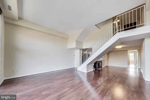 3101 New Mexico Ave NW Unit 847, Washington, DC 20016 - unfurnished living room featuring wood finished floors, visible vents, baseboards, a high ceiling, and stairs