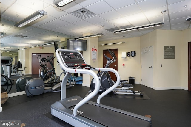 exercise room featuring a drop ceiling, visible vents, and baseboards