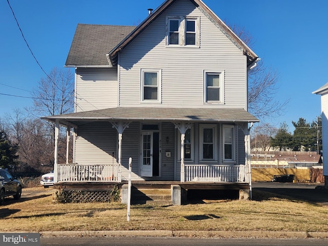 view of front of house featuring covered porch, roof with shingles, and a front yard