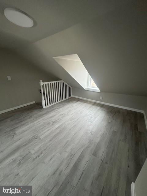 additional living space with lofted ceiling, wood finished floors, and baseboards