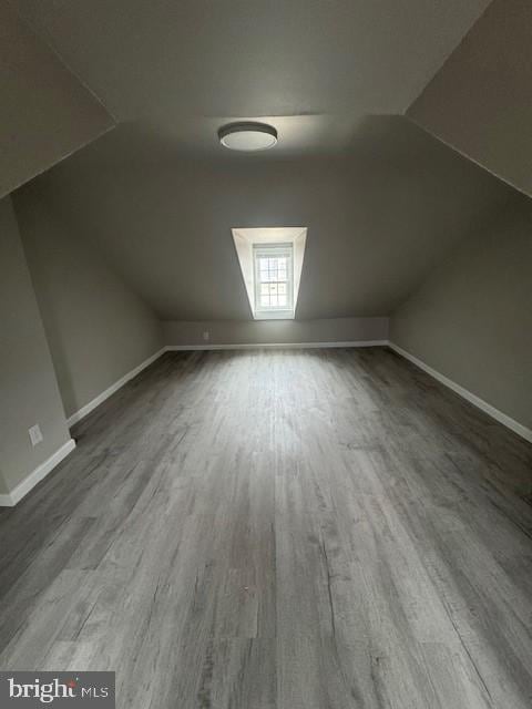 additional living space with lofted ceiling, baseboards, and wood finished floors