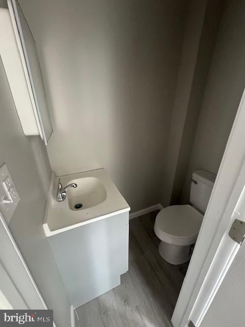 bathroom featuring baseboards, a sink, toilet, and wood finished floors