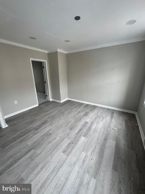 empty room with baseboards, dark wood-style flooring, and crown molding