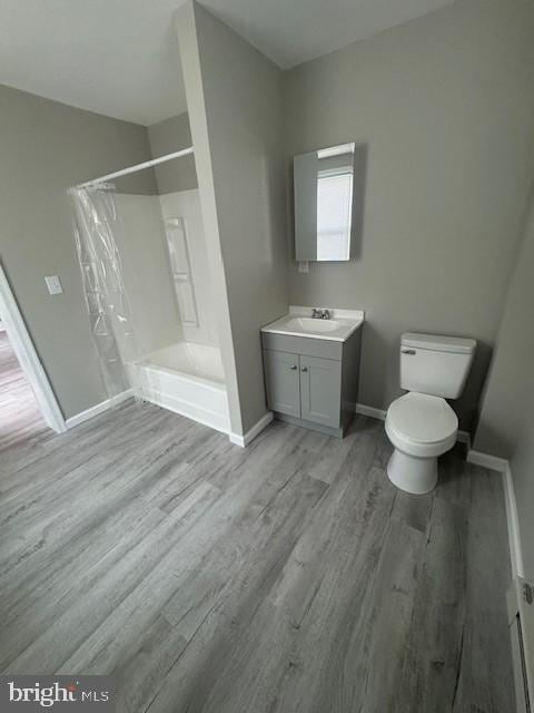 full bath with a shower with shower curtain, wood finished floors, toilet, and baseboards