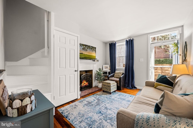 living room featuring a warm lit fireplace and wood finished floors