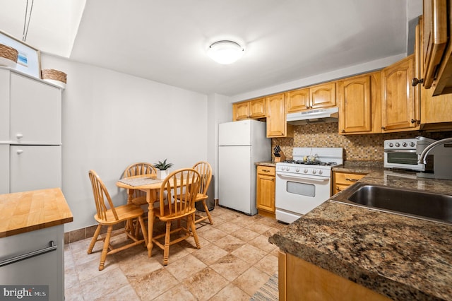 kitchen with white appliances, tasteful backsplash, wood counters, under cabinet range hood, and a sink