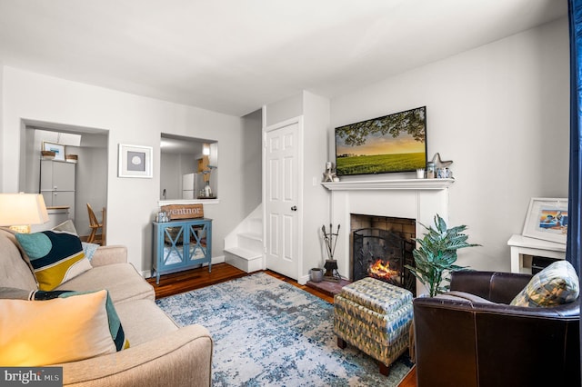 living area featuring a lit fireplace, baseboards, and wood finished floors