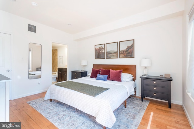 bedroom with ensuite bath, light wood-style flooring, visible vents, and baseboards