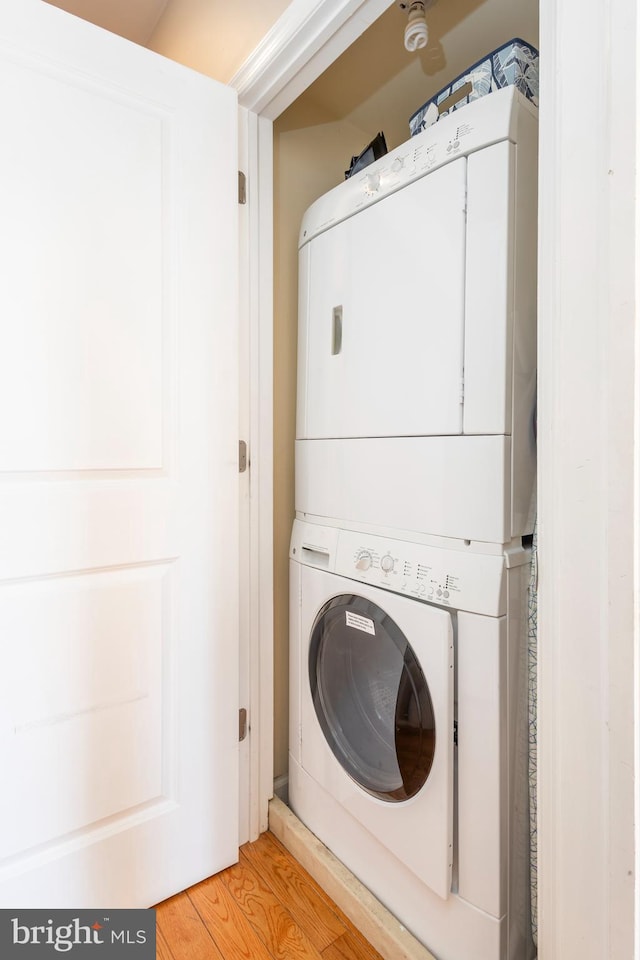 laundry room with light wood-type flooring, laundry area, and stacked washing maching and dryer