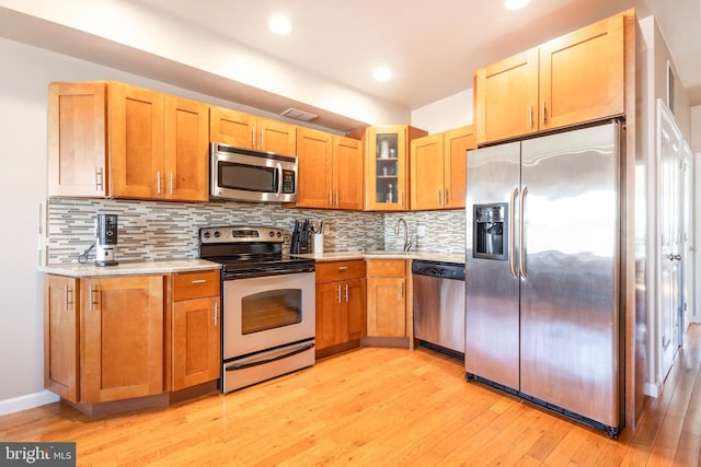 kitchen with light countertops, appliances with stainless steel finishes, a sink, and light wood-style flooring