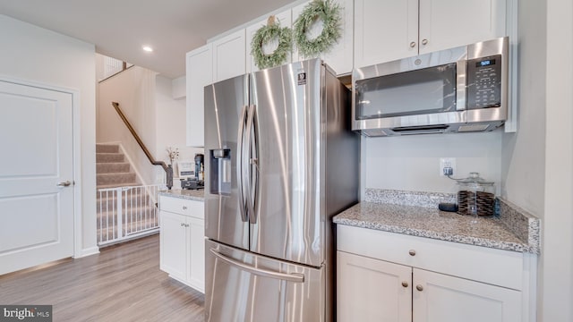 kitchen with light stone counters, recessed lighting, white cabinetry, appliances with stainless steel finishes, and light wood finished floors