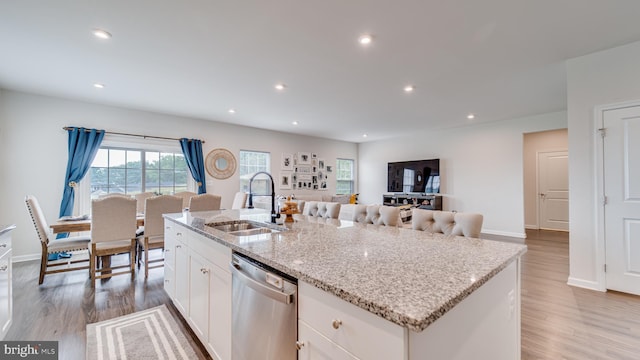 kitchen with white cabinets, dishwasher, light wood-style flooring, and a sink