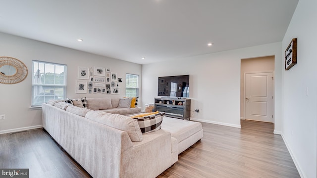 living area featuring baseboards, recessed lighting, wood finished floors, and a healthy amount of sunlight