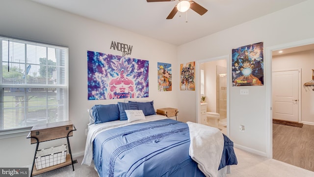 bedroom featuring a ceiling fan, light colored carpet, baseboards, and ensuite bathroom